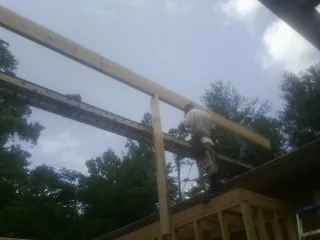 Carpenter setting a ridge beam over a new addition frame — Ice Dam Removal by Roofing Brothers in Cana