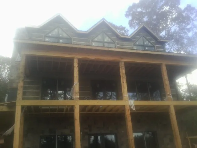 Dormers and porch framing on a large log home under construction — Roof Coating work by our crew in Cana