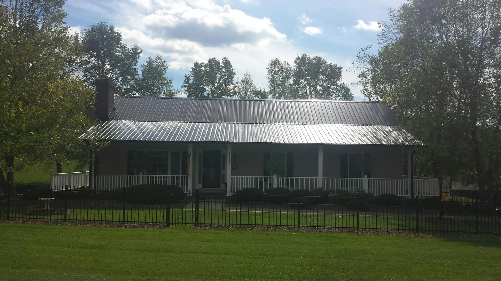 Gray metal roof on a brick ranch with a full width front porch — Gutter Guard Installation work by our crew in Cana