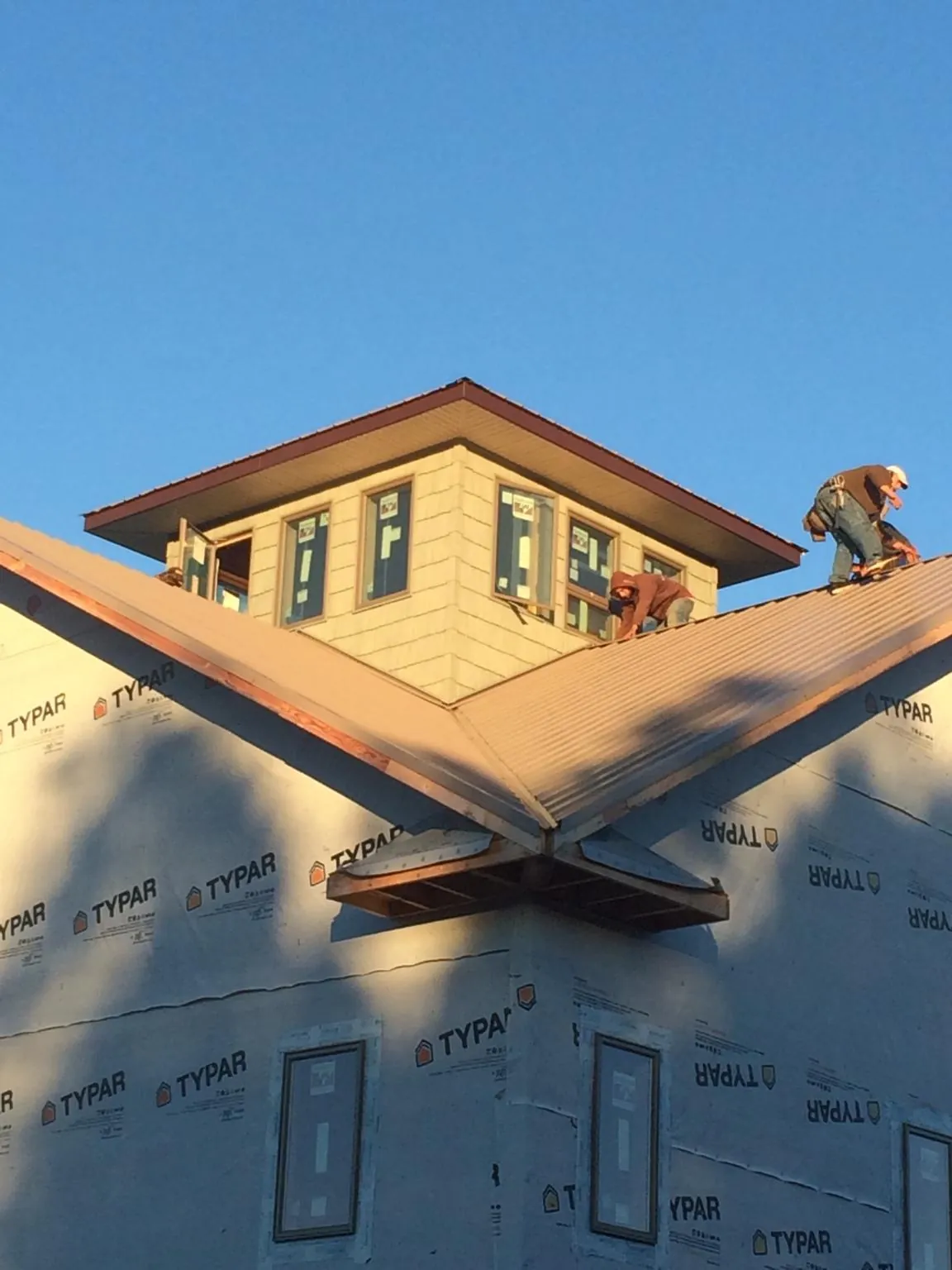 Roofers working around a rooftop cupola on a new metal roof at sunset — Roof Waterproofing in Cana by Roofing Brothers